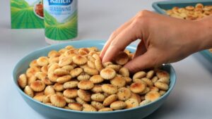 A Hand Reaches Into a Bowl of Golden, Ranch-Seasoned Oyster Crackers