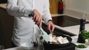 A Person Uses a Spatula to Sear Sliced King Oyster Mushrooms in A Skillet on The Stove